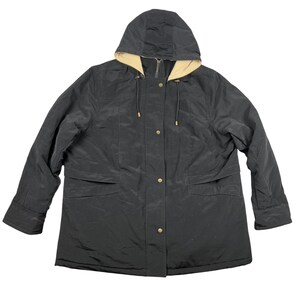 Puede incluir: Chaqueta negra con capucha y forro beige. La chaqueta tiene cierre de cremallera, botones a presión y dos bolsillos delanteros. La capucha tiene cordones. Una prenda de abrigo clásica.