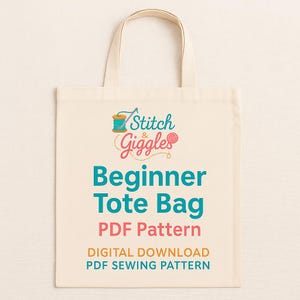 May include: Cream-colored tote bag with the text "Stitch & Giggles" and "Beginner Tote Bag PDF Pattern". The bag has a simple design with a handle, perfect for carrying sewing projects or other items.