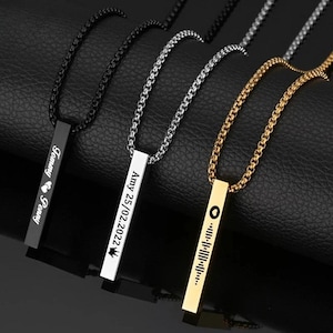 May include: Three personalised bar necklaces with black, silver, and gold chains. Each bar features engraved text. The black bar reads "Tommy ❤ Penny", the silver bar reads "Amy 25/02/2022", and the gold bar has a music code.