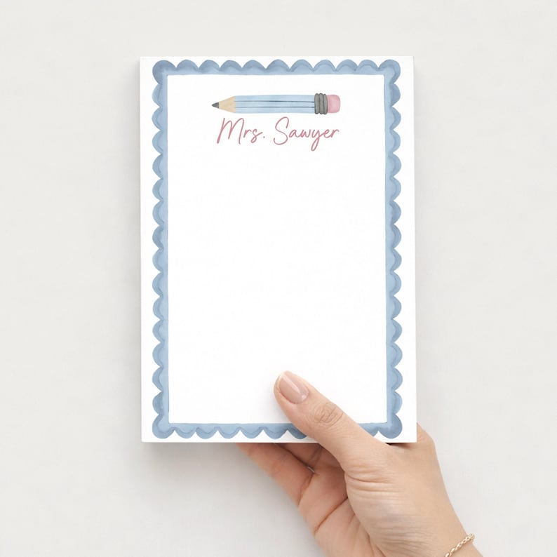 May include: A rectangular notepad with a white center and a scalloped light blue border. At the top, there is a watercolor illustration of a light blue pencil with a pink eraser. The text Mrs. Sawyer is printed in a pink script font below the pencil.