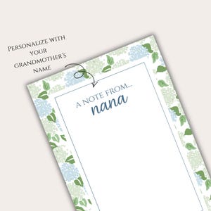 May include: A white notepad featuring a floral border of blue and green hydrangea flowers. The text "A note from... nana" is in a blue script font. The top left corner reads "Personalize with your grandmother's name."