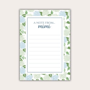 May include: A rectangular notepad featuring a floral design of blue and green hydrangeas on a white backdrop. The notepad has a white interior with lined pages and the text "A NOTE FROM... mimi" in blue.