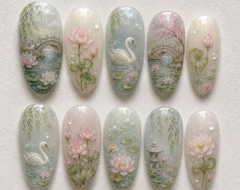 May include: A set of ten oval-shaped press-on nails featuring detailed hand-painted scenes of white swans, pink lotus flowers, green lily pads, arched stone bridges, and a small pagoda, all set against a soft, translucent, and pearlescent background.