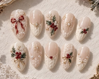 May include: A set of ten press-on nails featuring a cream-colored base with festive holiday designs including red bows, green holly leaves, red berries, gold stars, white snowflakes, pearl accents, and textured cable knit patterns.