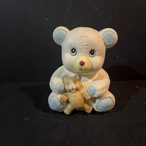 May include: A white ceramic mug with a black handle and the text "But First, Coffee" in a black, bold font. The mug is on a white surface.