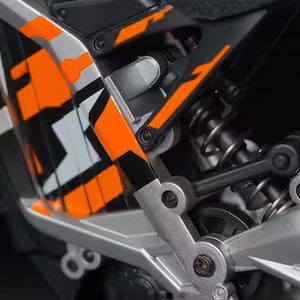 “Macro shot of the orange-black-silver mini off-road bike display model, highlighting frame structure and suspension details.”