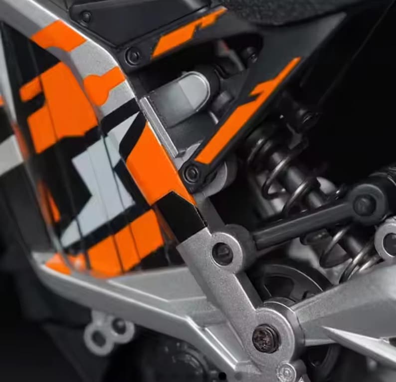 “Macro shot of the orange-black-silver mini off-road bike display model, highlighting frame structure and suspension details.”
