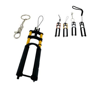May include: A collection of miniature bicycle suspension fork keychains. The keychains feature a black and gold color scheme, with a silver keychain ring and a black lanyard. The forks are detailed and realistic, with a variety of styles.