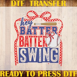 May include: A DTF transfer design with the text "Hey Batter Batter Swing" in red and blue, featuring a baseball and bat graphic. The design is framed by a red ribbon with a checkered pattern.