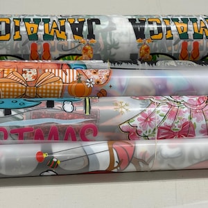 May include: Rolled sheets of patterned paper. Designs include the word "Jamaica" with tropical imagery, pumpkins, bows, and the word "Christmas". Other patterns feature floral and abstract designs.