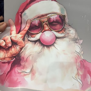 May include: A watercolour illustration of Santa Claus wearing sunglasses and a red hat, blowing a pink bubble. Santa is giving the peace sign with his left hand. The image has a whimsical and festive feel.