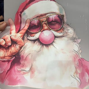 May include: A watercolor illustration of Santa Claus wearing gold-rimmed sunglasses and a red hat with a white trim. Santa is blowing a pink bubble and making a peace sign with his fingers. The image has a festive, whimsical vibe.