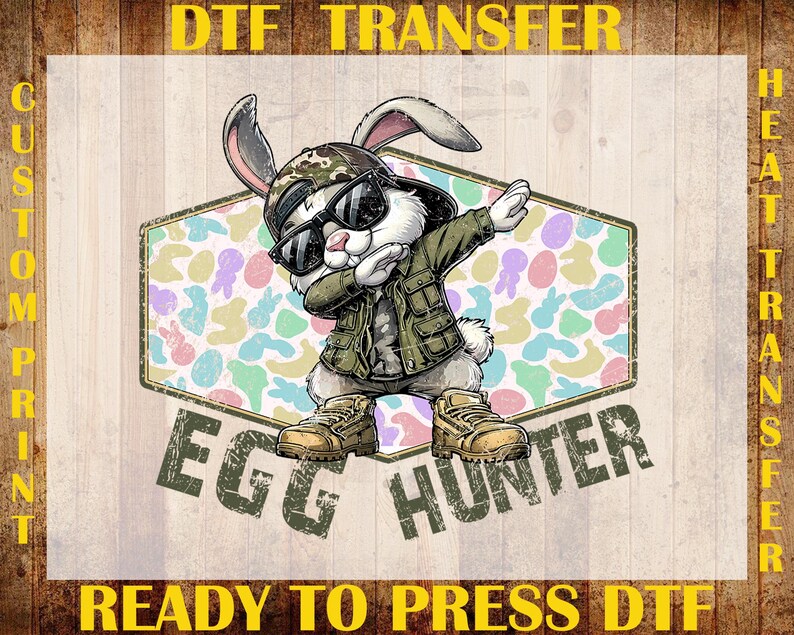 May include: A DTF transfer featuring a cartoon rabbit wearing sunglasses, a camouflage hat, and a green jacket, dabbing. The text "EGG HUNTER" is below the rabbit, and the text "DTF TRANSFER" and "READY TO PRESS DTF" are above and below the image.