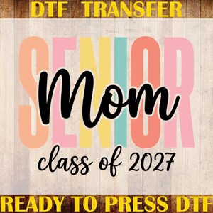 May include: A DTF heat transfer design featuring the word SENIOR in large, pastel-colored block letters behind the black script text Mom and the black text class of 2027. The border includes the yellow text DTF TRANSFER, CUSTOM PRINT, and READY TO PRESS DTF.