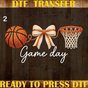 May include: A DTF transfer design featuring a basketball, a bow, and a basketball net. The words "Game day" are written in cursive. The words "DTF TRANSFER", "CUSTOM PRINT", "HEAT TRANSFER", and "READY TO PRESS DTF" are also present.