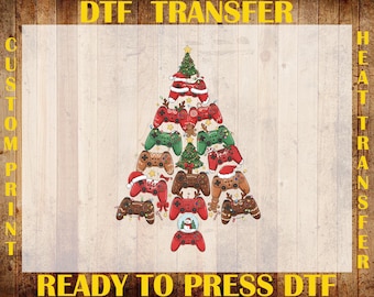May include: A Christmas tree design made of video game controllers in red, green, and brown. The controllers are decorated with Santa hats, reindeer antlers, and gingerbread men. The words "DTF TRANSFER", "CUSTOM PRINT", and "READY TO PRESS DTF" are displayed.