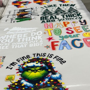 May include: A printed sheet with multiple designs. These include colourful birds, Christmas trees, the phrase "Real Thick and Sprucey," and a Grinch character with Christmas lights. Text includes "I'm Fine. This is Fine."