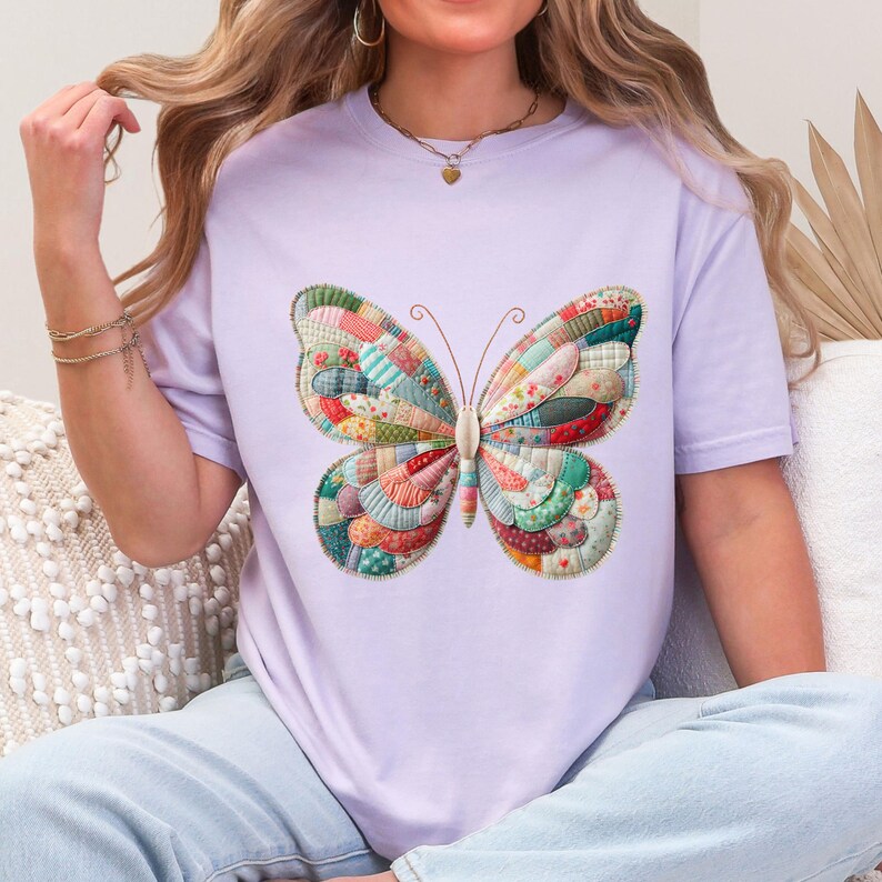 Puede incluir: Camiseta lila con un gran dise&ntilde;o de mariposa. Las alas de la mariposa est&aacute;n hechas de patchwork en varios colores, incluyendo rojo, verde y azul. La camiseta es de estilo casual.