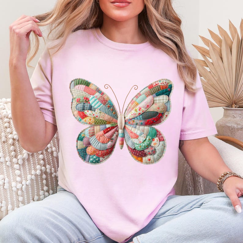 Puede incluir: Camiseta rosa claro con un dise&ntilde;o de mariposa grande. La mariposa est&aacute; hecha de tela de patchwork colorida con una variedad de patrones y colores, incluyendo rojo, azul, verde y amarillo. La camiseta es de estilo casual.