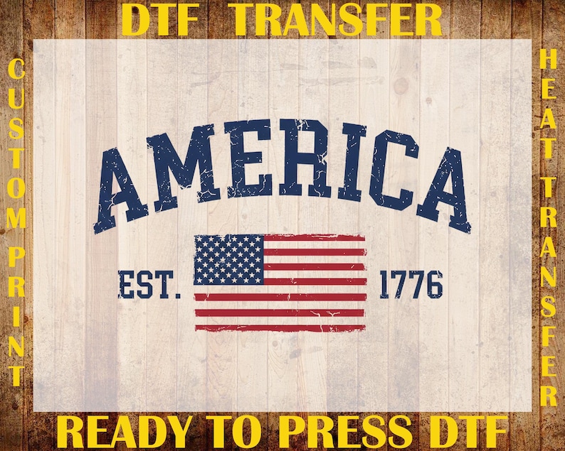 May include: A DTF transfer sheet featuring the word AMERICA in a distressed navy blue font, positioned above a graphic of the United States flag. The text EST. 1776 appears on either side of the flag. The design includes yellow text borders.