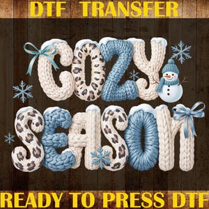 May include: A DTF transfer design with the words "COZY SEASON" in a knitted font, featuring snowflakes and a snowman. The letters have a mix of cream, blue, and leopard print patterns, with bows and snow accents. The words "DTF TRANSFER", "CUSTOM PRINT", and "READY TO PRESS DTF" are also visible.