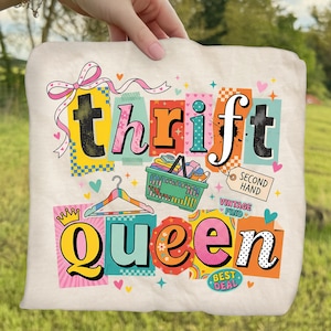 May include: Cream-colored tote bag with the words "thrift queen" in colorful, block letters. The design includes a pink bow, a clothes hanger, a shopping basket, and the words "second hand" and "vintage find".