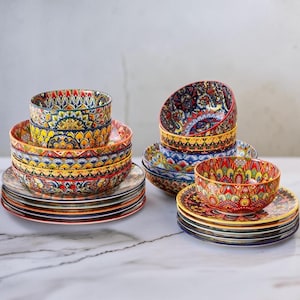 Puede incluir: Una colección de cuencos y platos de cerámica con patrones intrincados y coloridos en tonos rojo, amarillo, azul y verde. El juego de vajilla incluye cuencos apilados y platos a juego con diseños geométricos y florales detallados.