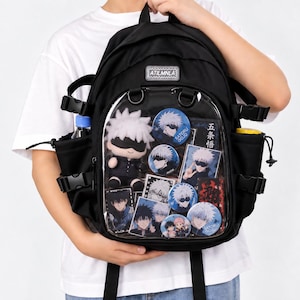 Pode incluir: Uma mochila preta com um bolso frontal transparente preenchido com vários itens de coleção de anime, incluindo uma figura de pelúcia, botões redondos e cartões retangulares retratando personagens com cabelos brancos e vendas pretas.