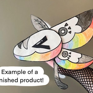May include: A colorful, handmade paper craft resembling a stylized insect or creature. The wings are decorated with rainbow colors, black, and white. The text "Example of a finished product!" is in a white speech bubble.