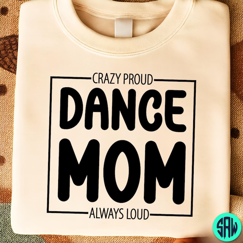 May include: Cream-colored sweatshirt with the text "CRAZY PROUD DANCE MOM ALWAYS LOUD" in a black, bold font. The text is enclosed in a black rectangular frame. The sweatshirt has a crew neck.