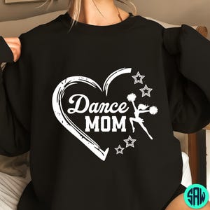 May include: Black sweatshirt with a white graphic. The graphic features the words "Dance MOM" inside a heart shape, with stars and a cheerleader silhouette. The design is printed on the front of the sweatshirt.