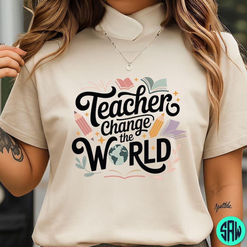May include: A beige t-shirt featuring the phrase "Teacher Change the World" in black script. The design incorporates colourful illustrations of pencils, books, and a globe. Ideal for educators.