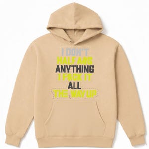 May include: A tan hoodie with a front pocket and a drawstring hood. The front of the hoodie features the text "I DON'T HALF ASS ANYTHING I PACK IT ALL THE WAY UP" in a mix of colors including yellow, gray, and black.