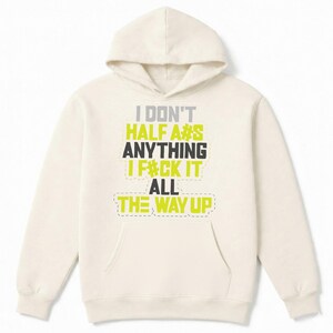May include: Cream-colored hoodie with a front pocket and hood. The front of the hoodie features the text "I DON'T HALF A#S ANYTHING I F#CK IT ALL THE WAY UP" in a mix of gray, black, and yellow-green block letters.