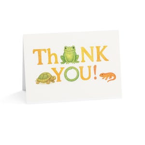 Könnte beinhalten: Eine weiße Grußkarte mit den Worten "Thank You" in Gelb und Grün. Die Karte zeigt Illustrationen einer Schildkröte, eines Frosches und einer Eidechse. Der Frosch ist grün, die Schildkröte ist braun und grün, und die Eidechse ist orange.