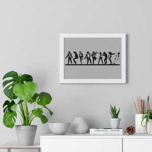 May include: A framed print featuring black silhouettes of people in various dance poses. The figures are arranged in a horizontal line against a gray background. The white frame adds a clean, modern aesthetic to the artwork.