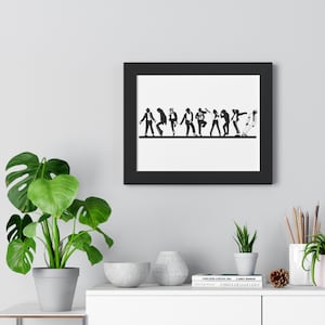 May include: Black framed wall art featuring a line of stylized figures in various dance poses. The figures are in black against a white background. The artwork is displayed on a gray wall, with a green plant and other decorative items in the foreground.