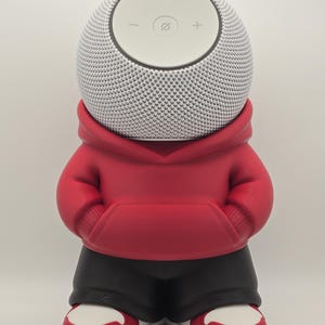 May include: A white spherical smart speaker with a top control panel featuring a minus sign, a plus sign, and a microphone mute icon. The speaker is encased in a red hooded sweatshirt, black pants, and red and white sneakers.