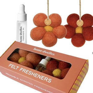 May include: A display of Home Dweller felt fresheners. The image shows a box of felt balls, a bottle of fragrance oil, and two flower-shaped felt air fresheners. The felt balls and flowers are orange and yellow.