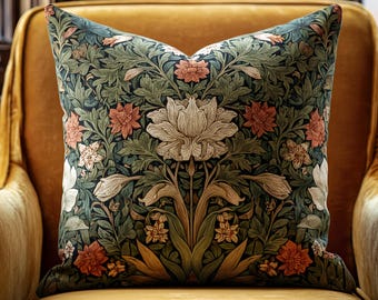May include: Square decorative pillow with a floral pattern in shades of green, peach, and cream. The pillow is placed on a yellow velvet armchair, creating a contrast in textures and colors. The design features stylized flowers and foliage.
