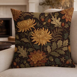 Pode incluir: Uma almofada quadrada com uma estampa botânica escura e atmosférica. O design apresenta grandes flores de crisântemo amarelo-dourado e laranja queimado, folhas de carvalho verdes, pequenas bolotas e bagas vermelhas num fundo castanho escuro.