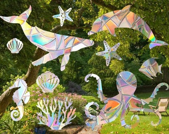 Puede incluir: Decoraciones iridiscentes de vida marina, incluyendo una ballena, un delfín, estrellas de mar, un caballito de mar, un pulpo, un pez, coral y conchas. Los diseños geométricos coloridos se presentan sobre un fondo natural al aire libre.