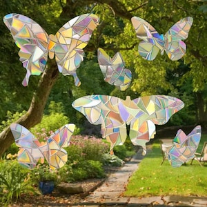 May include: A set of six iridescent butterfly window clings, each with a stained glass design. The butterflies are various sizes and are arranged on a green lawn with a stone path.