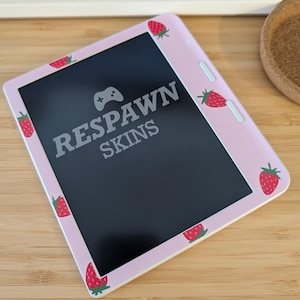 May include: A pink electronic device skin featuring a black screen and the text "RESPAWN SKINS". The skin is adorned with red strawberry designs. A gaming controller icon is above the text.