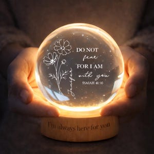 Puede incluir: Un globo de cristal brillante con un diseño floral y las palabras "DO NOT fear, FOR I AM with you, Isaiah 41:10" y el nombre "Jennifer". El globo se encuentra sobre una base de madera que dice "I'm always here for you".