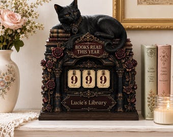 May include: A decorative black cat figurine resting on a stack of books atop a mechanical counter. The structure features dark ornate detailing, red roses, and text reading "BOOKS READ THIS YEAR" and "Lucie's Library" with three rotating number dials.