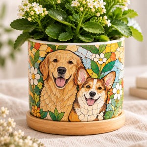 May include: A cylindrical ceramic planter featuring a colorful mosaic-style illustration of a Golden Retriever and a Corgi surrounded by flowers. The planter sits on a circular light-colored wooden base and contains a green leafy plant.