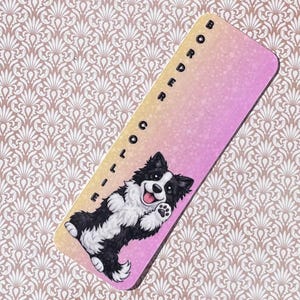Op de afbeelding: Een bladwijzer met een zwart-wit illustratie van een Border Collie. De bladwijzer heeft een gradiënt achtergrond van geel, roze en paars. De tekst "BORDER COLLIE" is verticaal op de bladwijzer gedrukt.
