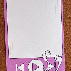 Può includere: Blocco note rettangolare con bordo lilla chiaro e interno bianco. La parte inferiore del blocco note presenta un design di lettore musicale con pulsanti di riproduzione, riavvolgimento e avanzamento rapido, insieme a auricolari bianchi.