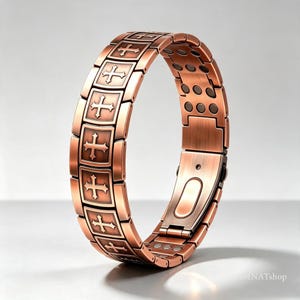 May include: A copper-toned link bracelet featuring a series of rectangular panels, each embossed with a raised cross design. The interior of the bracelet displays a row of small, circular magnetic inserts along the metal links and a clasp.